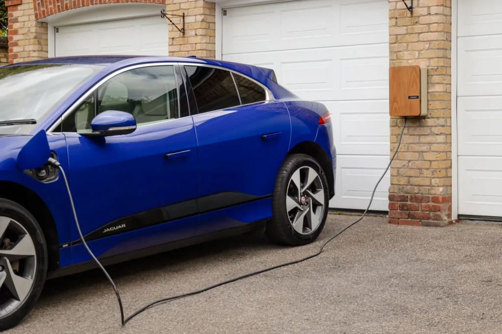 Borne de recharge murale installée dans un garage résidentiel, câble branché sur un véhicule électrique
